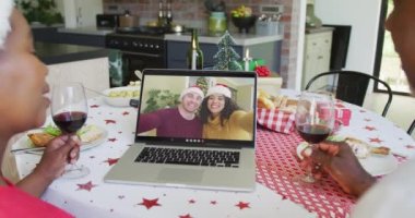 Şaraplı Afro-Amerikalı çift, dizüstü bilgisayarlarını ekranda çift olarak Noel 'de görüntülü konuşma yapmak için kullanıyorlar. Noel, şenlik ve iletişim teknolojisi.