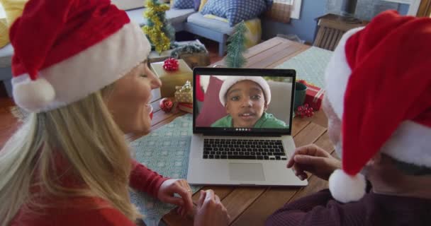 Усміхнена Кавказька Пара Капелюхами Санти Використовує Ноутбук Різдвяного Відеодзвінка Хлопчиком — стокове відео