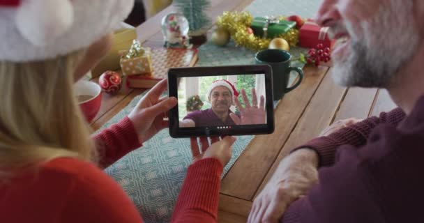用石碑为屏幕上的男人打圣诞视频电话 笑笑戴着桑塔帽子的高加索夫妇 圣诞节 节日和通信技术 — 图库视频影像