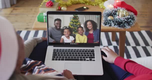 アフリカ系アメリカ人の母親と娘がクリスマスのビデオ通話にラップトップを使用しています クリスマスやお祭りや通信技術は — ストック動画