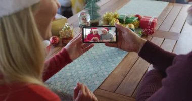 Noel Baba şapkalı beyaz bir çift Noel 'de ekranda çift olduğu için akıllı telefon kullanıyor. Noel, şenlik ve iletişim teknolojisi.