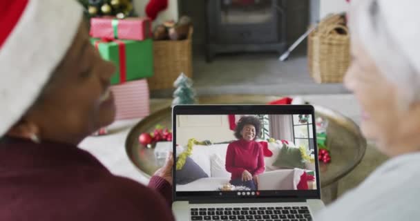两个不同的高级女友用笔记本电脑和屏幕上的女人进行圣诞视频通话 圣诞节 节日和通信技术 — 图库视频影像