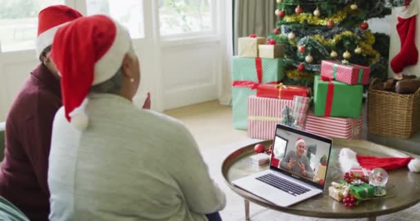 スクリーン上の男性とクリスマスのビデオ通話のためのラップトップを使用して2人のシニア多様な女性の友人 クリスマスやお祭りや通信技術は — ストック動画