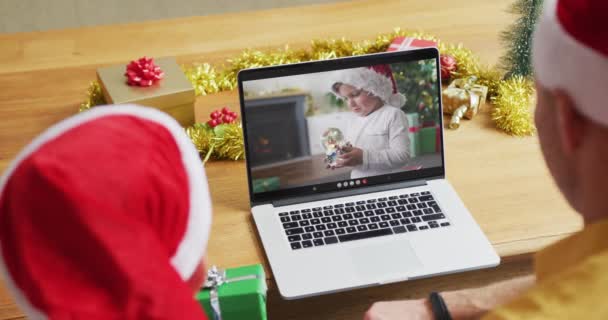 クリスマスのビデオ通話のためのラップトップを使用してサンタの帽子を持つ息子と白人の父 画面上の男の子と クリスマスやお祭りや通信技術は — ストック動画