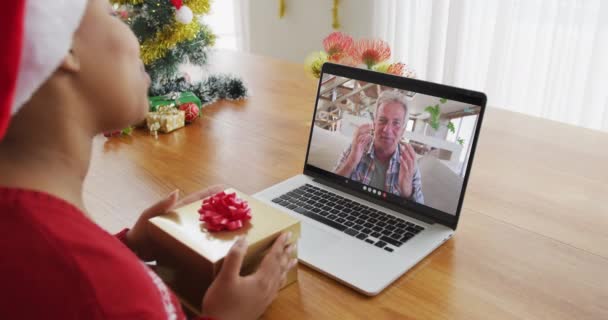 クリスマスのビデオ通話のためにラップトップを使用してサンタの帽子を持つアフリカ系アメリカ人女性 画面上の男 クリスマスやお祭りや通信技術は — ストック動画