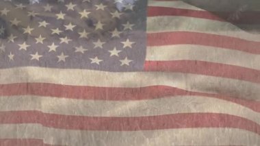 Amerikan bayrağının buğday tarlasında dalgalanması ve hasat makinesini birleştirmesi. Vatanseverlik, bağımsızlık ve tarım kavramı dijital olarak üretilen video.