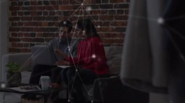 Ofisteki kanepede dizüstü bilgisayarla çalışan erkek ve kadın meslektaşlar arasındaki bağlantı ağının animasyonu. küresel iletişim ağı teknolojisi konsepti dijital olarak oluşturulmuş video.