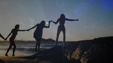 Gün batımı kumsalında el ele tutuşan kadın arkadaşların parlayan iletişim ağının animasyonu. küresel iletişim teknolojisi, boş zaman ve seyahat konsepti dijital olarak oluşturulmuş video.