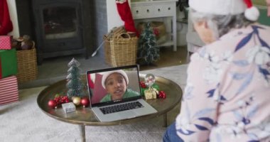 Üst düzey Kafkasyalı kadın ekrandaki çocukla Noel 'de el sallıyor ve laptopunu kullanıyor. Noel, şenlik ve iletişim teknolojisi.