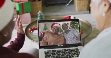 Çeşitli son sınıf kız arkadaşları ekranda aileleriyle birlikte yılbaşı videosu için el sallıyor ve dizüstü bilgisayar kullanıyorlar. Noel, şenlik ve iletişim teknolojisi.