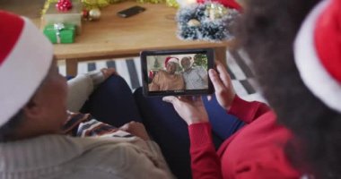 Afrika kökenli Amerikalı anne ve kız. Ekranda aileleriyle birlikte yılbaşı videosu için tablet kullanıyorlar. Noel, şenlik ve iletişim teknolojisi.