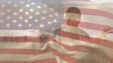 Amerikan bayrağının buğday tarlasında dikilen erkek çiftçi üzerinde dalgalanması. Vatanseverlik, bağımsızlık ve tarım kavramı dijital olarak üretilen video.