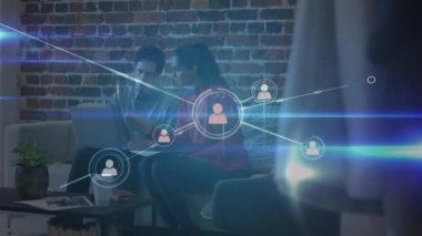 Ofisteki kanepede dizüstü bilgisayar kullanan kadın ve erkek meslektaşlar üzerindeki insan ikonlarının animasyonu. küresel iletişim ağı ve dijital arayüz teknolojisi konsepti dijital olarak oluşturulmuş video.