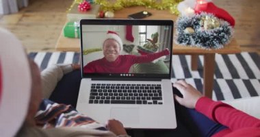 Afrika kökenli Amerikalı anne ve kız. Ekrandaki adamla yılbaşı videosu için dizüstü bilgisayar kullanıyorlar. Noel, şenlik ve iletişim teknolojisi.