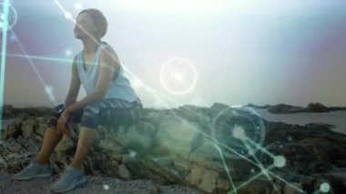 Sahilde egzersiz yaptıktan sonra dinlenen bir kadının üzerine parlayan iletişim ağının animasyonu. küresel iletişim teknolojisi, boş zaman ve seyahat konsepti dijital olarak oluşturulmuş video.