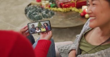 Gülümseyen Asyalı çift Noel 'de ekranda ailesiyle birlikte akıllı telefon kullanıyor. Noel, şenlik ve iletişim teknolojisi.