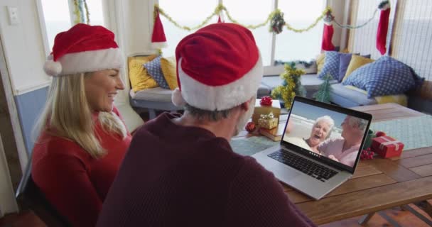 Sonriente Pareja Caucásica Con Sombreros Santa Usando Ordenador Portátil Para — Vídeo de stock