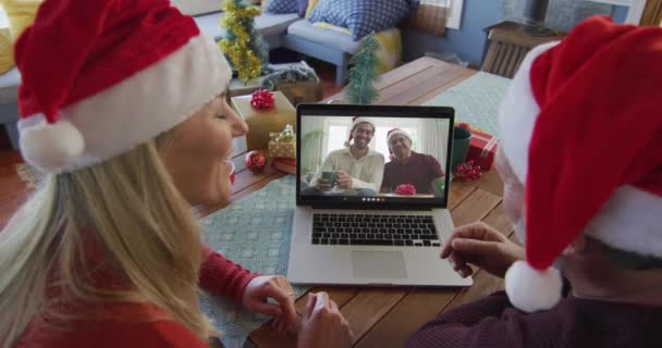 Sonriente Pareja Caucásica Con Sombreros Santa Usando Ordenador Portátil Para — Vídeo de stock