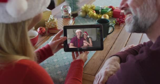 Leende Kaukasiska Par Med Santa Hattar Med Hjälp Surfplatta För — Stockvideo