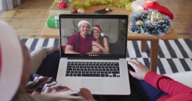 Afrika kökenli Amerikalı anne ve kız. Ekrandaki çiftle yılbaşı videosu için dizüstü bilgisayar kullanıyorlar. Noel, şenlik ve iletişim teknolojisi.