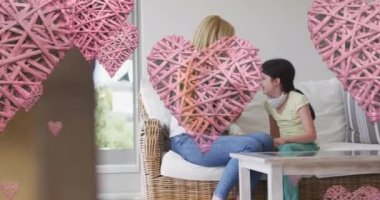 Kafkasyalı kadın ve evcil köpekle oynayan yüz maskesi takan kızının üzerinde kalp animasyonu. Evde aile zamanı covid 19 salgını sırasında dijital olarak üretilen video.