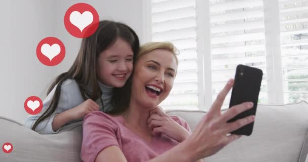 在家里用智能手机与高加索金发碧眼的母亲和女儿交谈时 心形像的动画 全球通信和社交媒体概念数字生成视频 — 图库视频影像