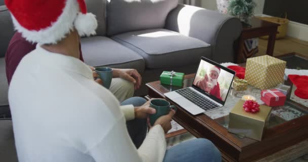 画面上のサンタとクリスマスのビデオ通話のためのラップトップを使用してサンタの帽子を持つ実父と息子 クリスマスやお祭りや通信技術は — ストック動画