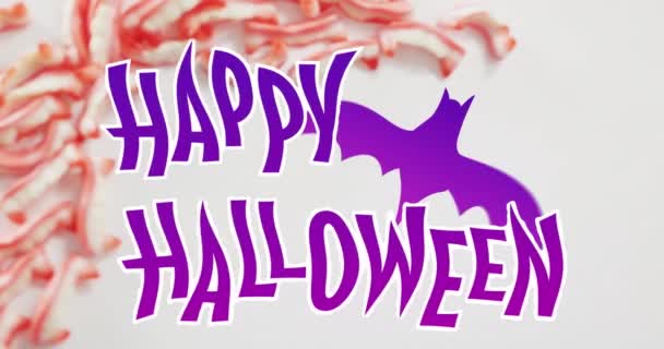 灰色の表面にハロウィンキャンディに対するバットアイコンとハッピーハロウィンテキストバナー ハロウィンのお祭りとお祝いのコンセプト — ストック動画
