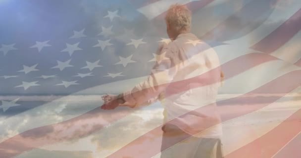 アメリカの国旗の上でビーチで踊る幸せな高齢者の白人夫婦のアニメーション アメリカの愛国心休日と退職の概念デジタルで生成されたビデオ — ストック動画