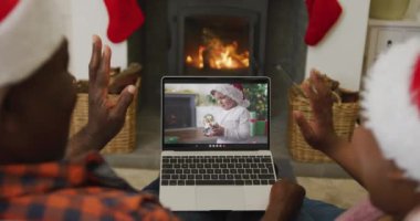 Noel Baba şapkalı Afro-Amerikalı çift, ekrandaki çocukla Noel 'de bilgisayar kullanıyorlar. Noel, şenlik ve iletişim teknolojisi.