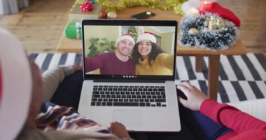 Afrika kökenli Amerikalı anne ve kız. Ekrandaki çiftle yılbaşı videosu için dizüstü bilgisayar kullanıyorlar. Noel, şenlik ve iletişim teknolojisi.