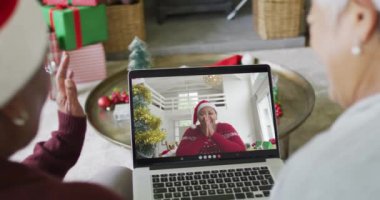 Çeşitli son sınıf kız arkadaşları ekrandaki kadınla birlikte dizüstü bilgisayarlarını kullanarak yılbaşı görüntüsü için el sallıyorlar. Noel, şenlik ve iletişim teknolojisi.