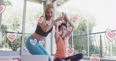 Kızıyla birlikte dizüstü bilgisayarla yoga yapan mutlu, beyaz bir kadının üzerinde hareket eden kalp animasyonu. Dijital ortamda oluşturulan videoda aile zamanı.
