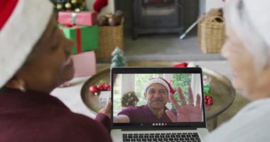 Gülümseyen çeşitli son sınıf kız arkadaşları, ekranda bir erkekle yılbaşı videosu için dizüstü bilgisayar kullanıyorlar. Noel, şenlik ve iletişim teknolojisi.