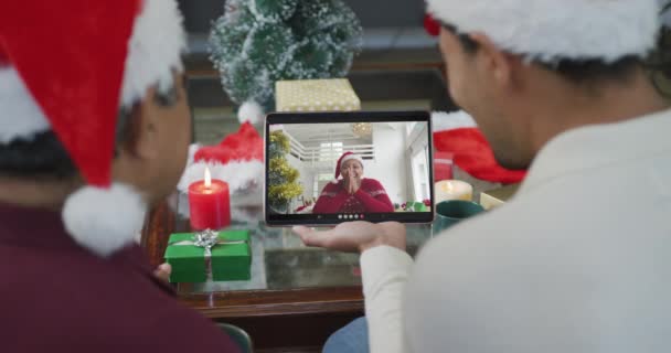 画面上の女性とクリスマスのビデオ通話のためのタブレットを使用してサンタの帽子を持つ出産の父と息子 クリスマスやお祭りや通信技術は — ストック動画