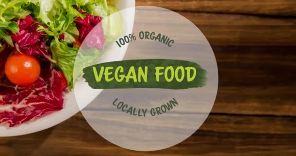 木製のテーブルの上に新鮮なサラダのプレート上に緑のビーガンフードテキストのアニメーション ビーガンの日 有機野菜の生産と健康的な食事のコンセプトデジタル生成されたビデオ — ストック動画