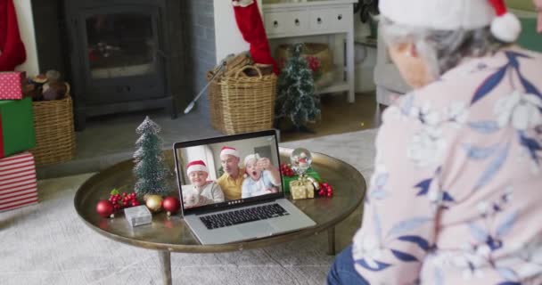 白种人老年妇女戴着圣诞礼帽 用笔记本电脑在屏幕上与家人进行圣诞视频通话 圣诞节 节日和通信技术 — 图库视频影像