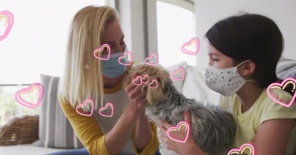 卡卡妇女和她的女儿戴着面具和宠物狗玩耍时的心形动画 科维德19大流行病期间家庭在家里的时间数字制作视频 — 图库视频影像