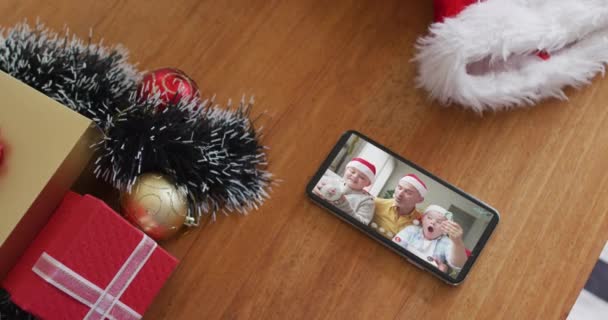 スマートフォンのクリスマスビデオ通話でサンタの帽子で白人の家族を笑顔 クリスマスやお祭りや通信技術は — ストック動画