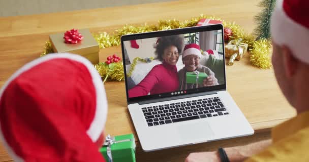 白种人的父亲和儿子戴着桑塔帽 他们用笔记本电脑在屏幕上与家人进行圣诞视频通话 圣诞节 节日和通信技术 — 图库视频影像