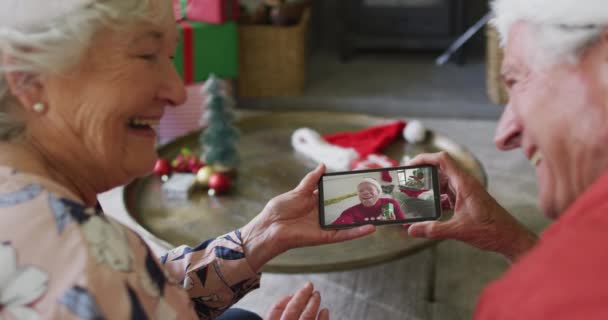 スマートフォンを使ってクリスマスのビデオ通話をする先輩の白人カップルを笑顔で画面上の男と クリスマスやお祭りや通信技術は — ストック動画
