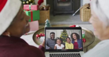 Birçok üst düzey bayan arkadaş, ekranda gülümseyen aile ile birlikte yılbaşı videosu için dizüstü bilgisayar kullanıyor. Noel, şenlik ve iletişim teknolojisi.