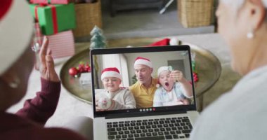 Birçok üst düzey bayan arkadaş, ekranda gülümseyen aile ile birlikte yılbaşı videosu için dizüstü bilgisayar kullanıyor. Noel, şenlik ve iletişim teknolojisi.