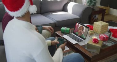 Noel Baba şapkalı melez baba ve oğul, ekrandaki çocukla Noel 'de görüntülü konuşma yapmak için dizüstü bilgisayar kullanıyorlar. Noel, şenlik ve iletişim teknolojisi.