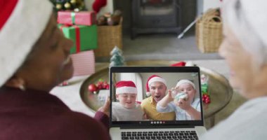 Birçok üst düzey bayan arkadaş, ekranda gülümseyen aile ile birlikte yılbaşı videosu için dizüstü bilgisayar kullanıyor. Noel, şenlik ve iletişim teknolojisi.