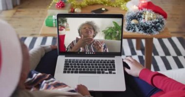 Afrika kökenli Amerikalı anne ve kız. Ekrandaki kadınla yılbaşı videosu için dizüstü bilgisayar kullanıyorlar. Noel, şenlik ve iletişim teknolojisi.