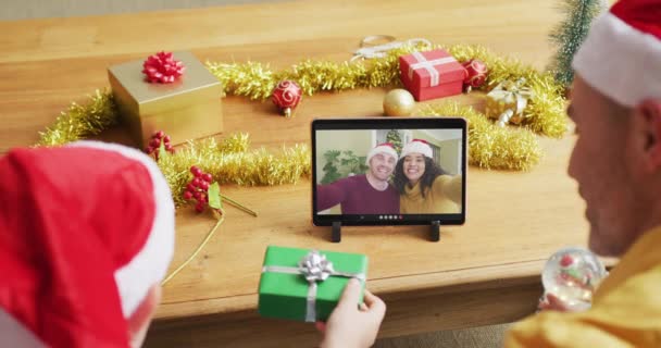 白种人的父亲和儿子与桑塔帽子使用石碑圣诞节视频通话夫妇在屏幕上 圣诞节 节日和通信技术 — 图库视频影像