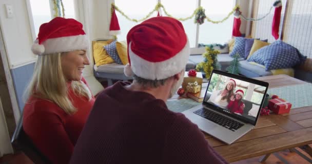 用笔记本电脑和家人一起在屏幕上进行圣诞视频通话 笑着带桑塔帽的高加索夫妇 圣诞节 节日和通信技术 — 图库视频影像