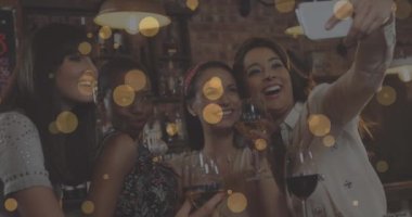 Partideki gülümseyen bayan arkadaşların selfie çekmesi üzerine parlayan sarı ışıkların animasyonu. parti ve kutlama konsepti dijital olarak oluşturulmuş video.