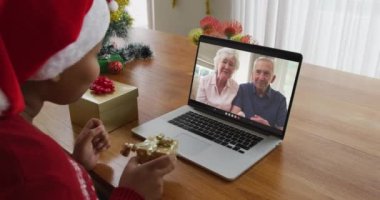 Noel Baba şapkalı Afro-Amerikalı bir kadın. Ekrandaki çiftle Noel 'de bilgisayar kullanıyor. Noel, şenlik ve iletişim teknolojisi.